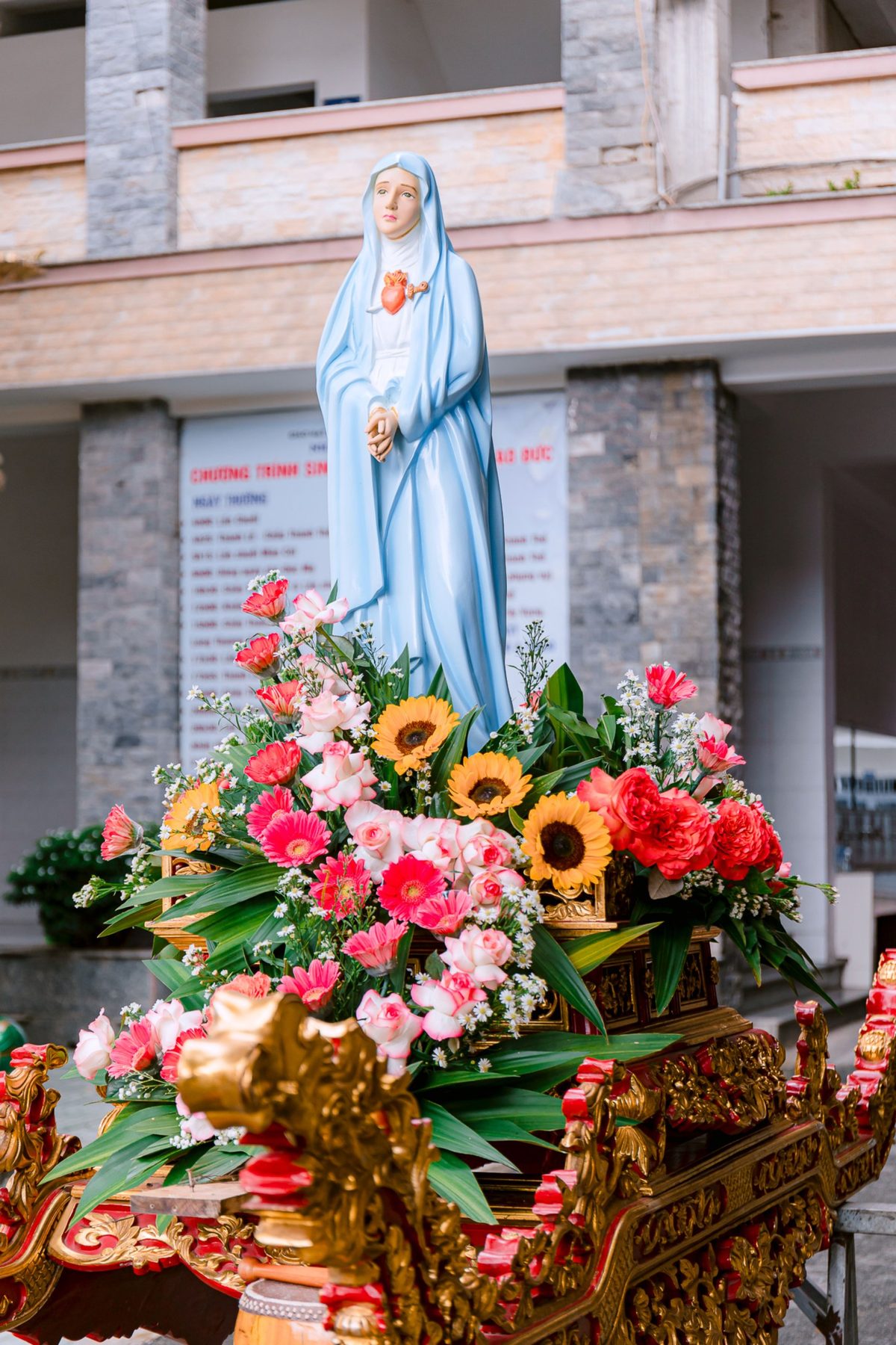 Andor de Nossa Senhora decorado com girassóis, gérberas, rosas bicolores, cravos e áster, pela Florabella, florista em Fafe