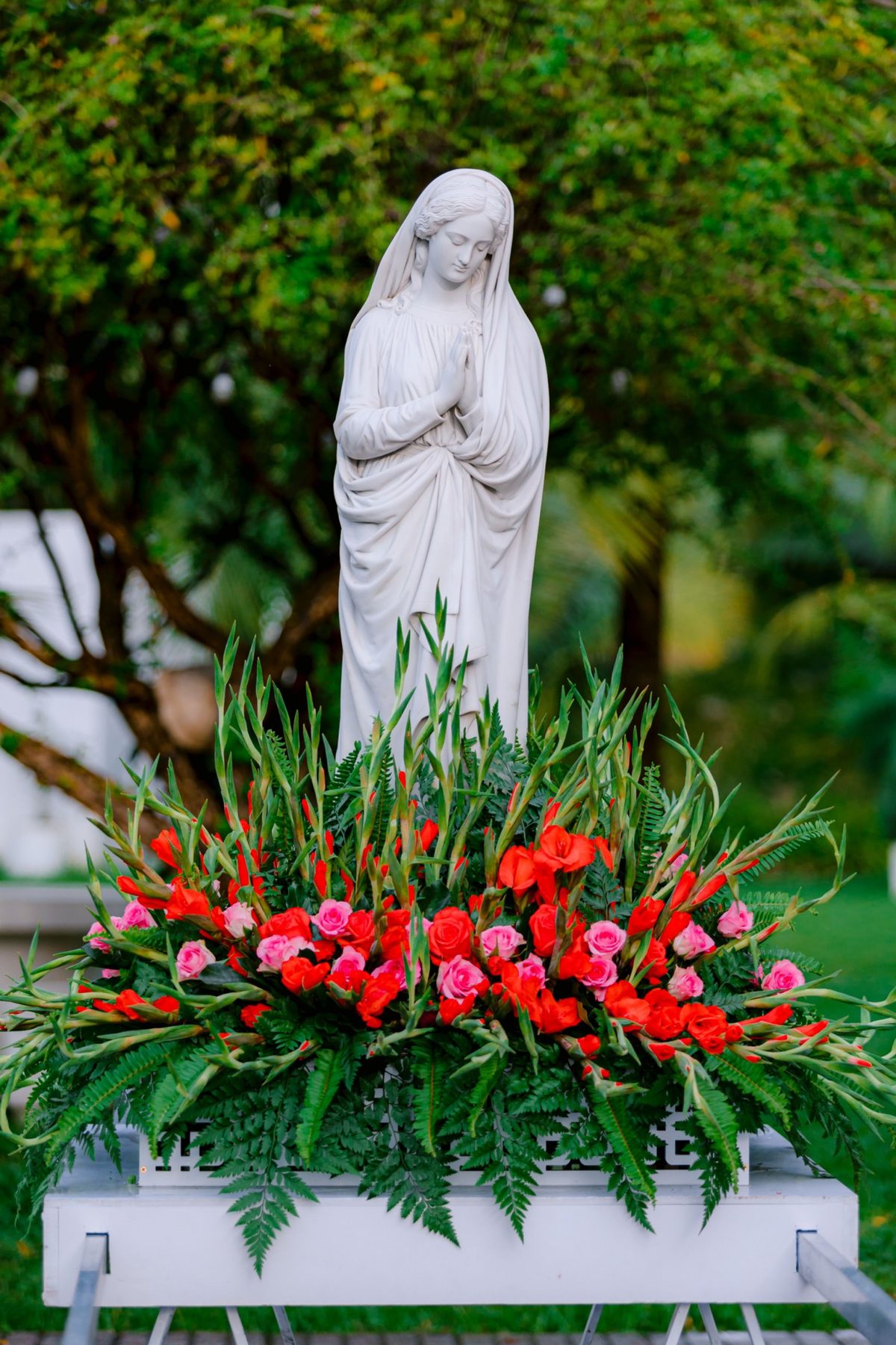 Andor de Nossa Senhora em pedra branca com gladíolos vermelhos, rosas cor-de-rosa e feto, pela Florabella, florista em Fafe