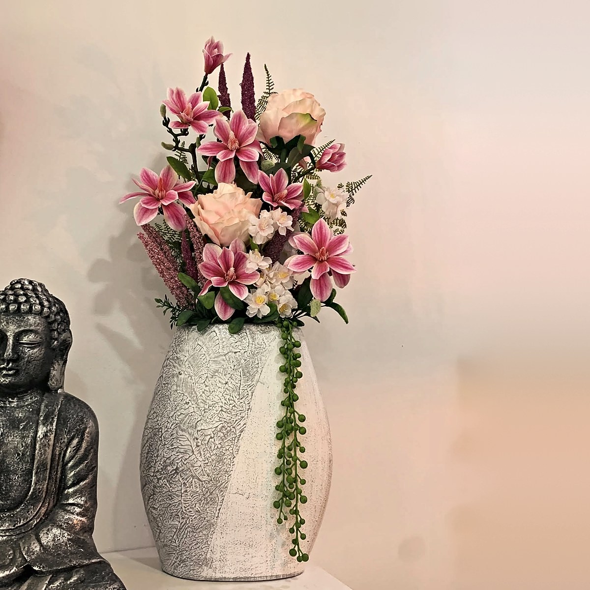 Arranjo de magnólias cor-de-rosa, rosas, flores brancas e colar-de-pérolas num vaso texturado branco e cinzento, peça de decoração da Florabella em Fafe