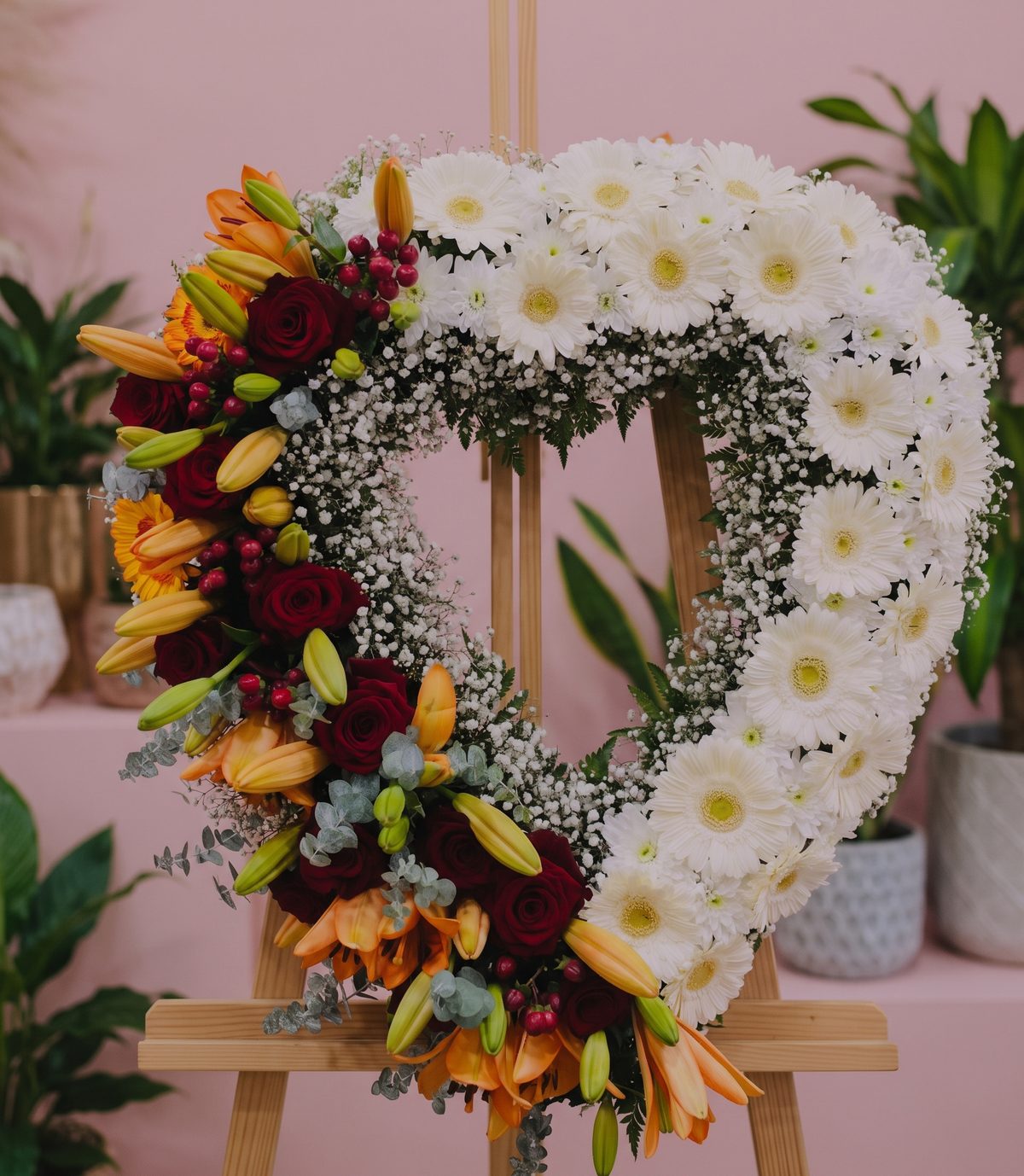 Coração de flores para funeral em tripé, com gérberas brancas, rosas vermelhas, lírios laranja, hipericão e eucalipto, feito pela Florabella em Fafe
