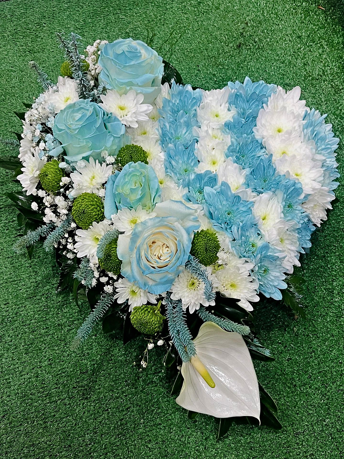 Coração de flores para funeral com rosas azuis, crisântemos azuis, brancos e verdes e antúrio branco, feito pela Florabella em Fafe