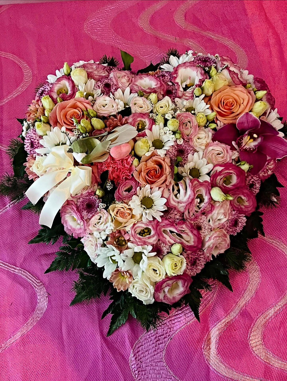 Coração de flores de homenagem com rosas salmão e brancas, lisianthus, margaridas, orquídea e laço creme, feito pela Florabella em Fafe