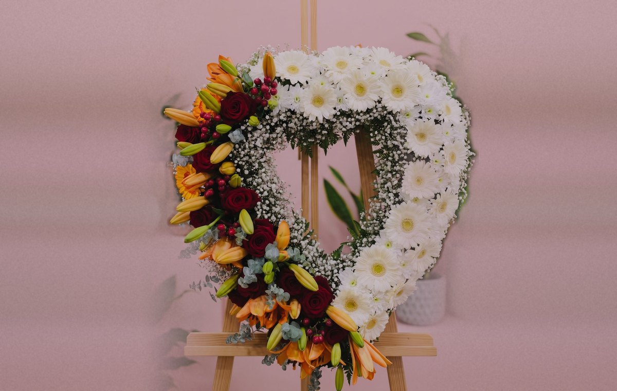 Coroa de flores em forma de coração para condolências, com gérberas brancas, rosas vermelhas e lírios, feita pela Florabella em Fafe