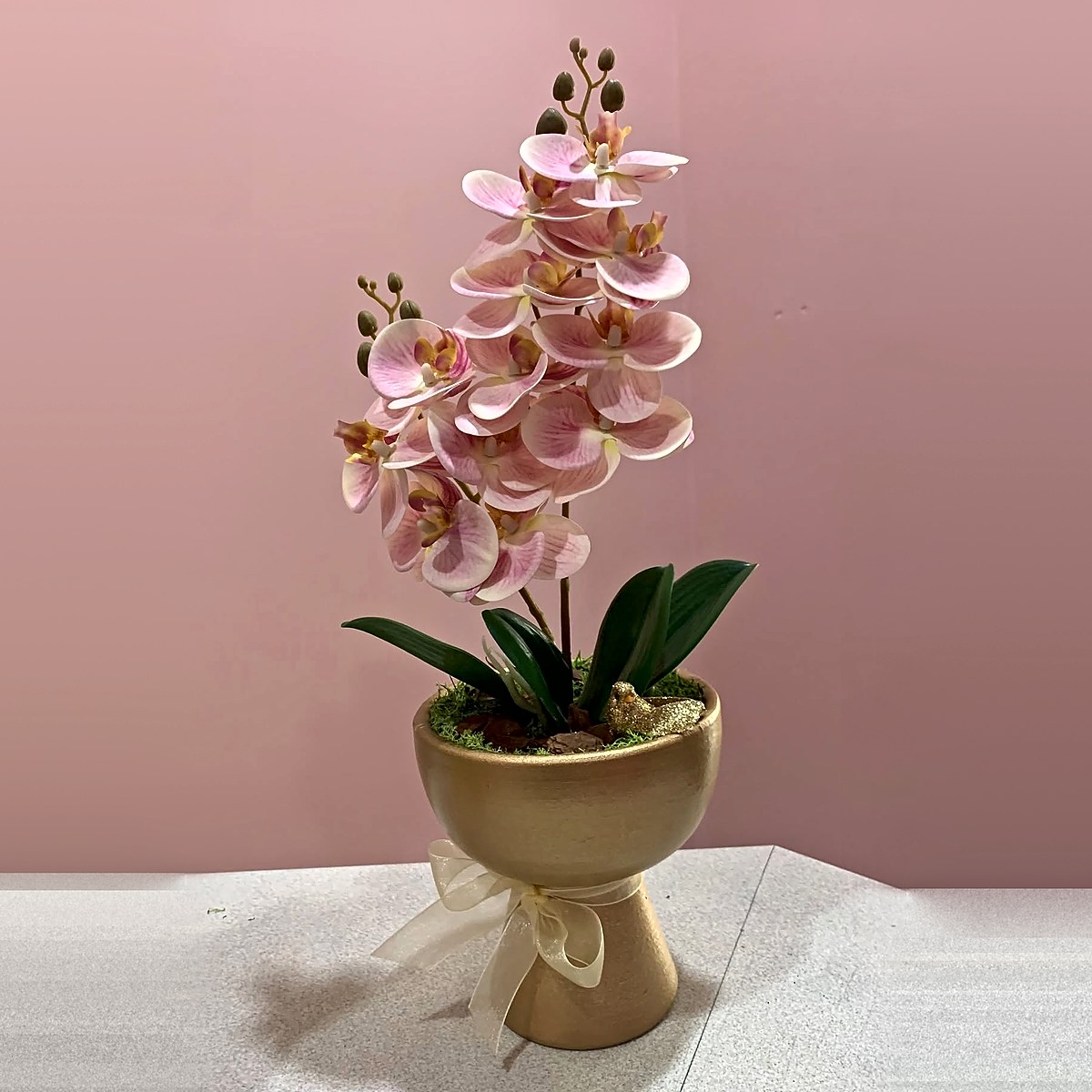 Orquídea cor-de-rosa numa taça dourada com laço de organza e pássaro dourado, peça de decoração da Florabella em Fafe