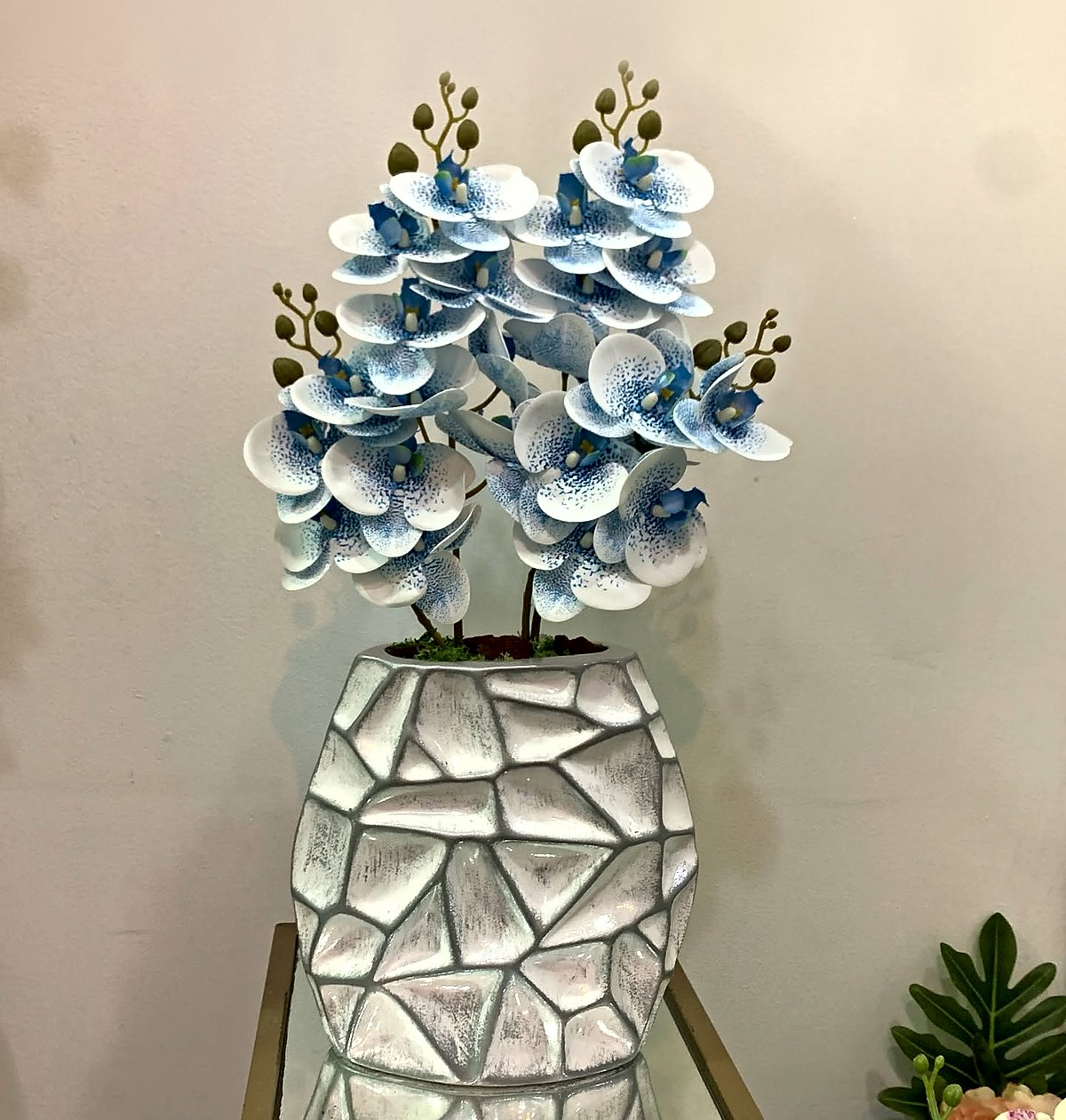 Orquídeas brancas e azuis num vaso prateado com relevo geométrico, peça de decoração da Florabella em Fafe
