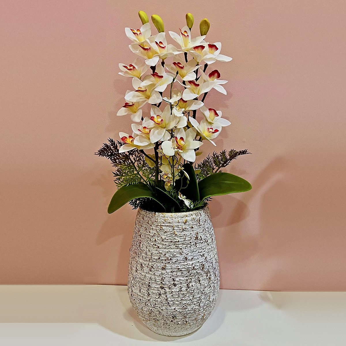 Orquídeas brancas com centro vermelho e amarelo, folhagem e fetos num vaso de cerâmica texturado, peça de decoração da Florabella em Fafe