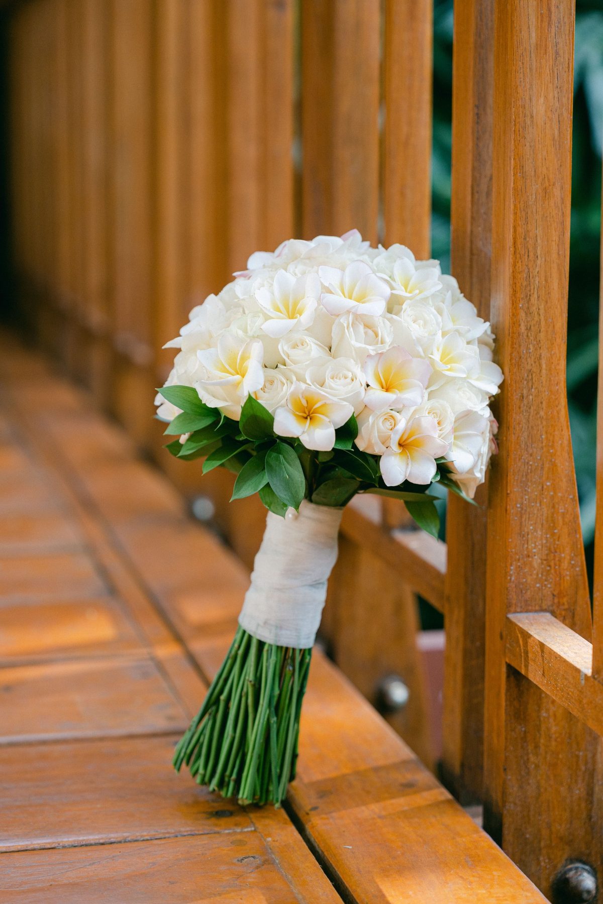 Ramo de noiva redondo com rosas brancas e frangipani, folhagem verde e pé forrado a tecido branco, feito pela Florabella em Fafe