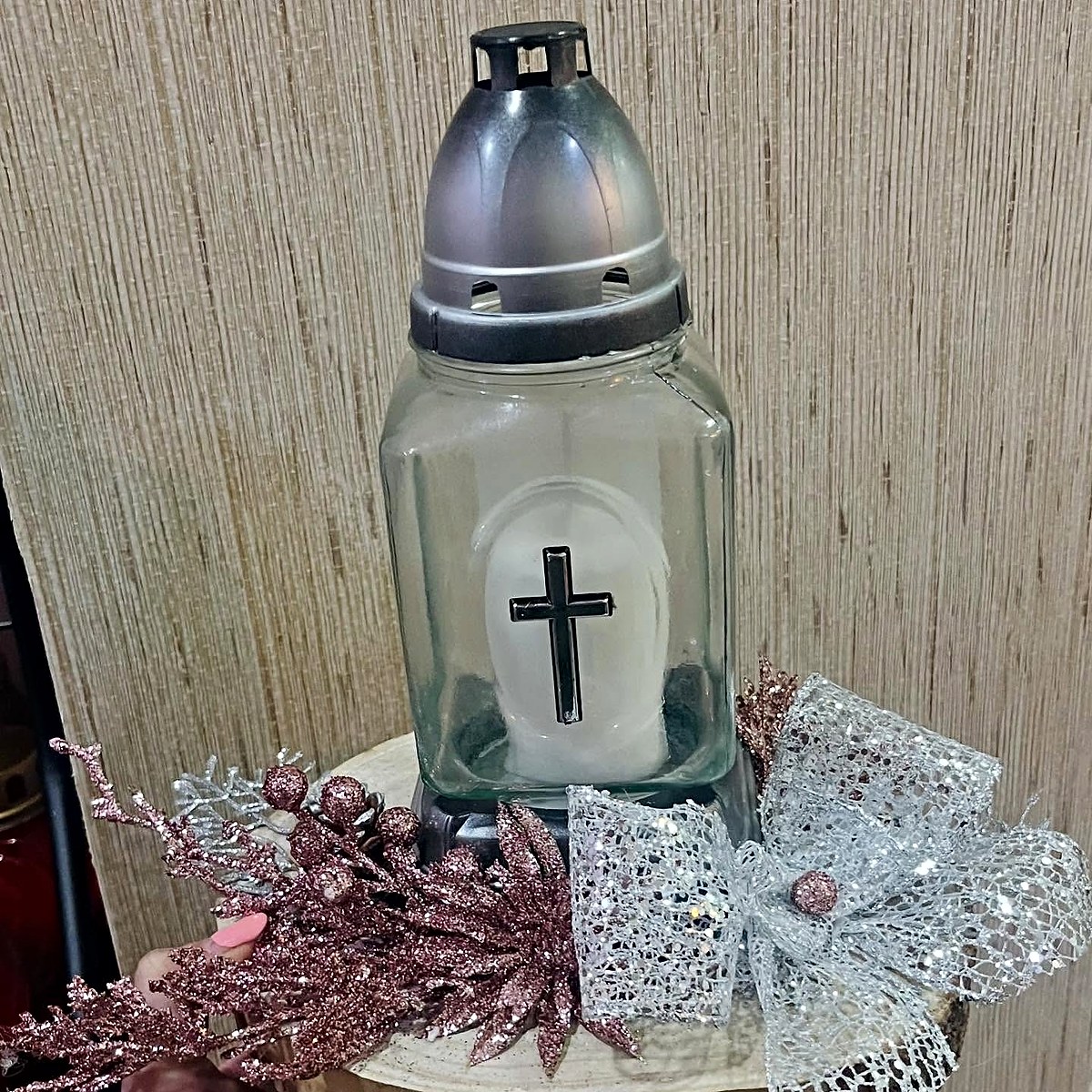 Vela de campa com cruz numa base de madeira, decorada com ramos cor-de-rosa com brilho e laço prateado, pela Florabella em Fafe