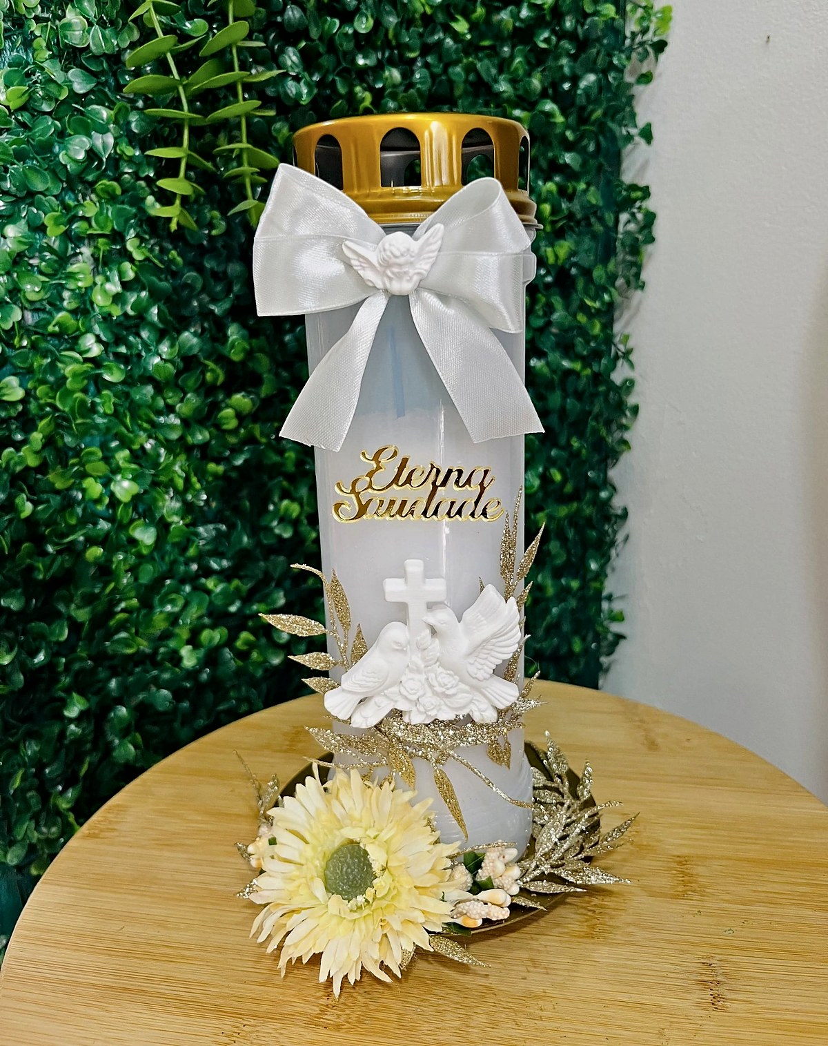 Vela personalizada «Eterna Saudade» com laço branco e anjo, pombas com cruz, folhas douradas e gérbera creme, feita pela Florabella em Fafe